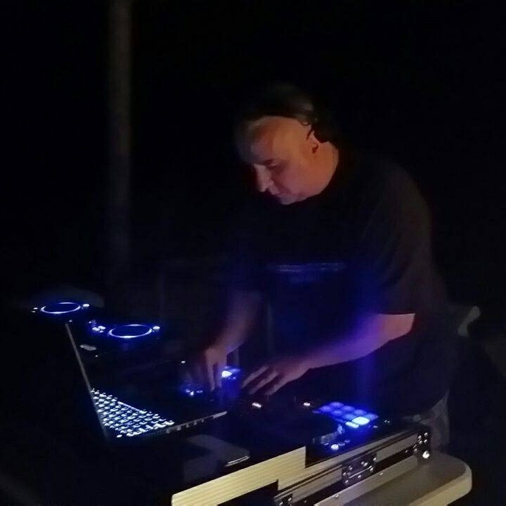 Juan Cardj mezclando con controlador y portátil bajo luces azules